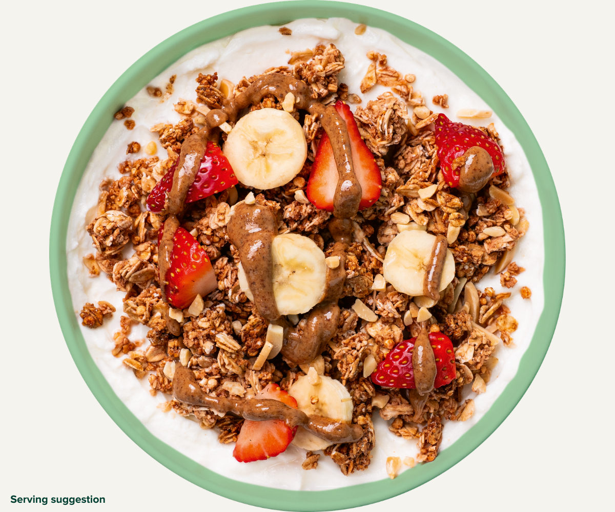 Angerichtete Granola Roasted Nuts Schüssel mit Joghurt, Erdbeeren, Bananen und Nussmus 
